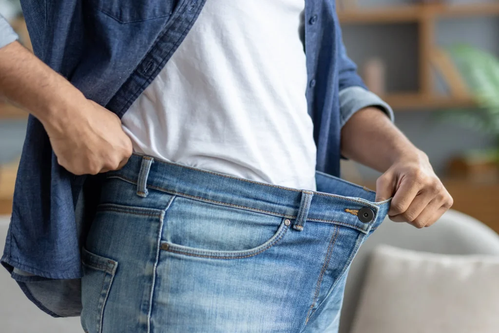 Person pinching loose jeans at waist to show weight loss success
