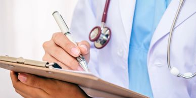 Healthcare provider writing on clipboard while wearing stethoscope