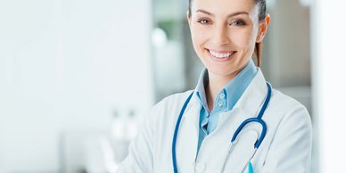 Smiling female healthcare provider wearing white coat and stethoscope in clinical setting