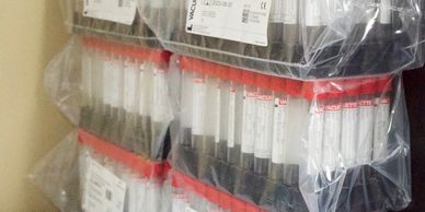 Organized medical specimen tubes with red and white labels in storage