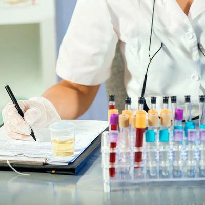 Medical technician recording notes while examining colorful laboratory test tubes