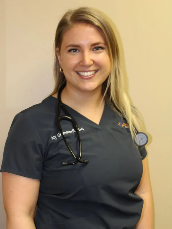 Healthcare provider in dark scrubs with stethoscope smiling at camera