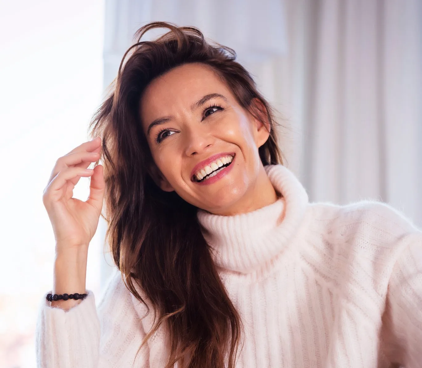 Woman smiling brightly while touching her hair