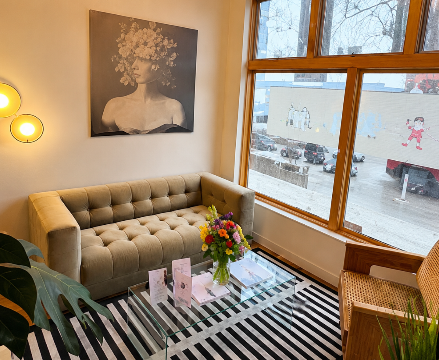 Urban Laser Denver reception area featuring tan sofa, portrait artwork, colorful flower arrangement, and wood-framed windows