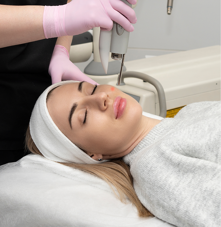Practitioner in pink gloves performing COâ‚‚ laser treatment on patient's face
