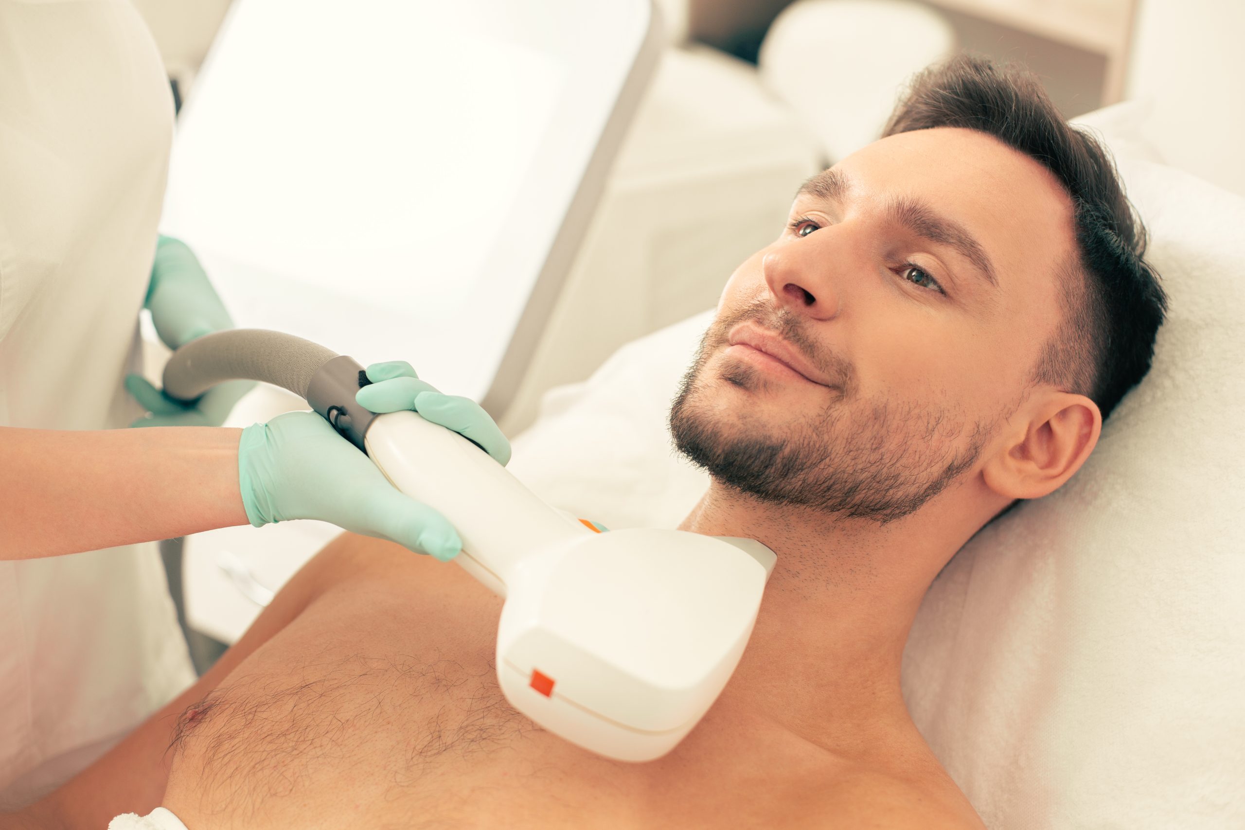Clinician performing laser hair removal on man's neck and chest area