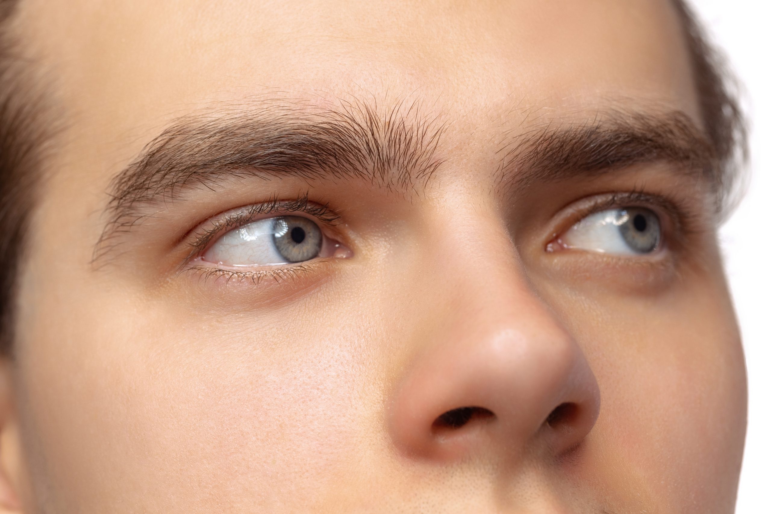 Close-up of man's face showing thick, dark eyebrows and blue eyes