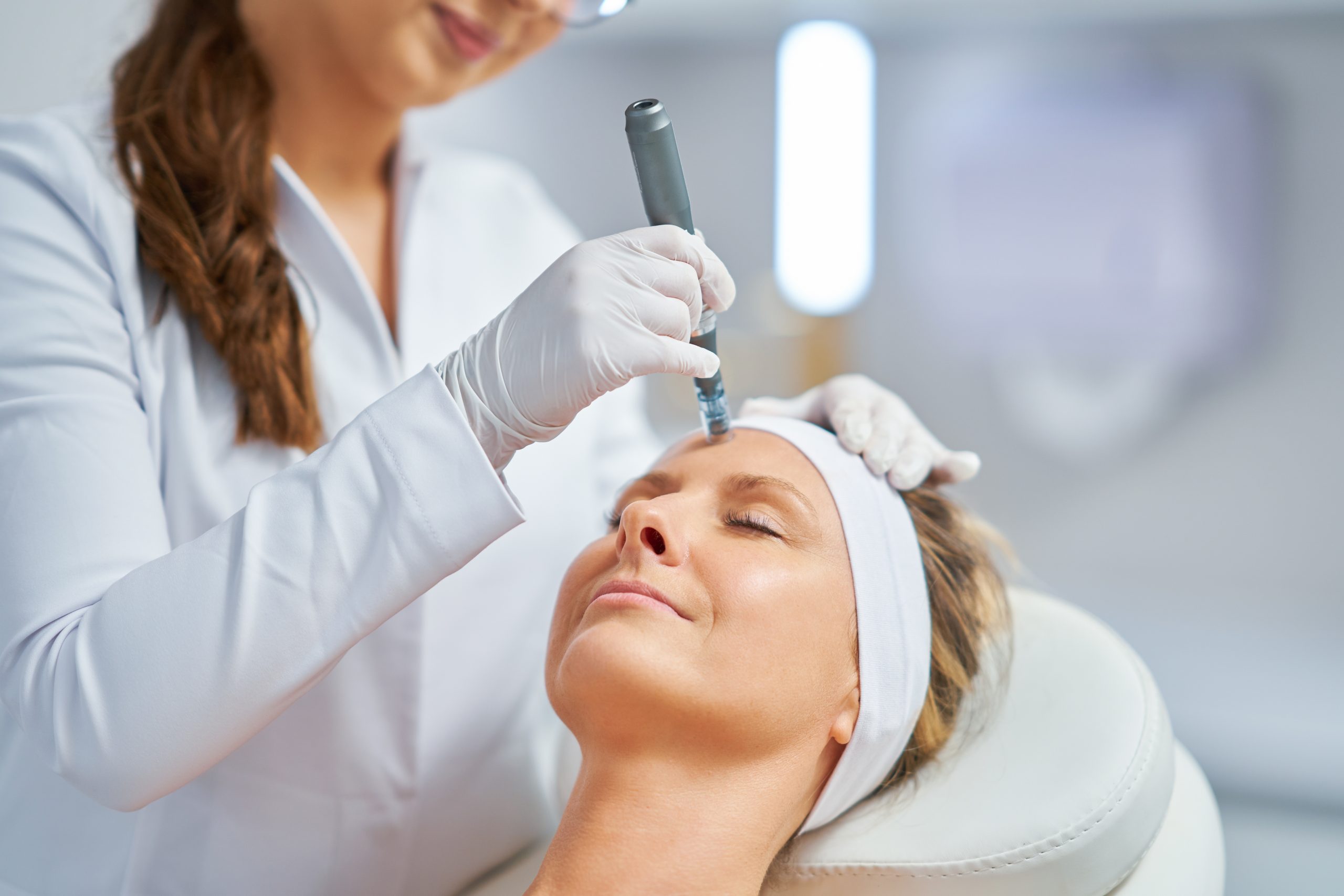 Aesthetician performing microneedling treatment on a patient's forehead in a medical spa setting