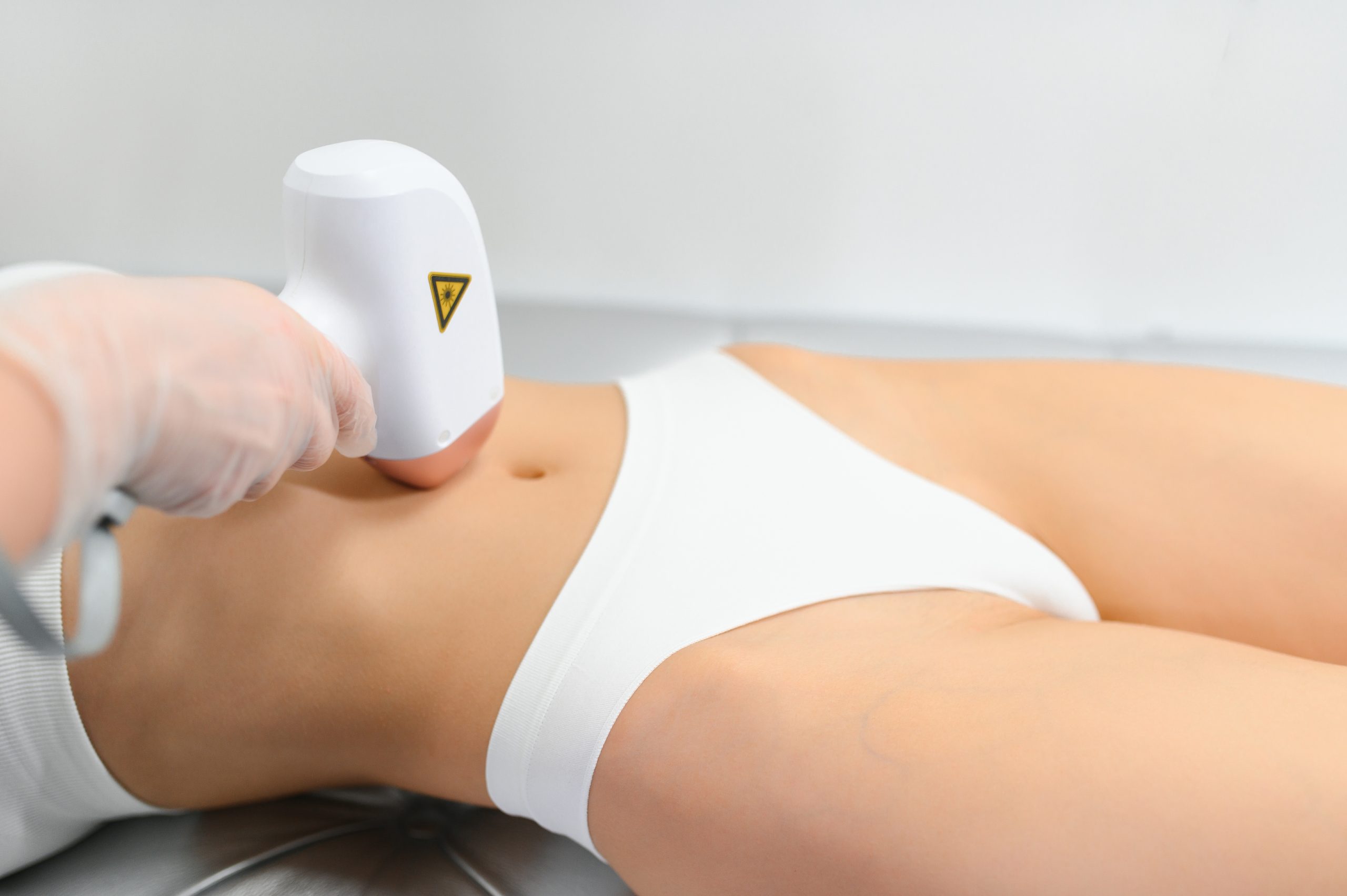 Practitioner applying laser hair removal device to patient's leg during treatment