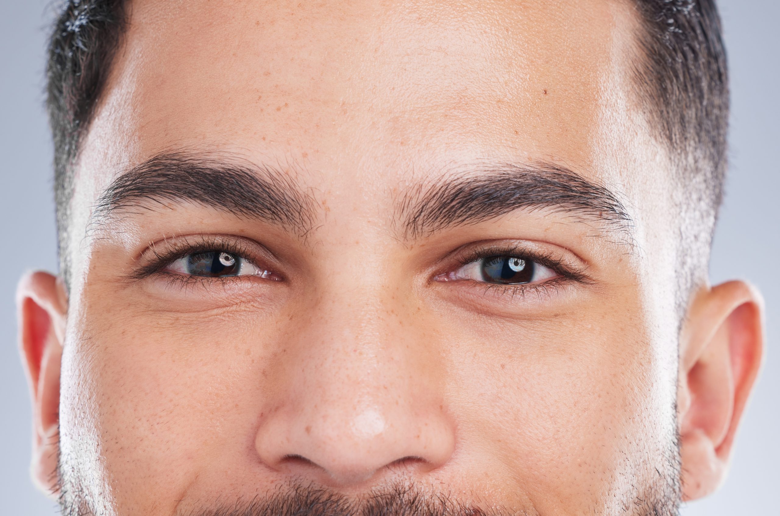 Man with well-groomed eyebrows and clear skin looking directly at camera