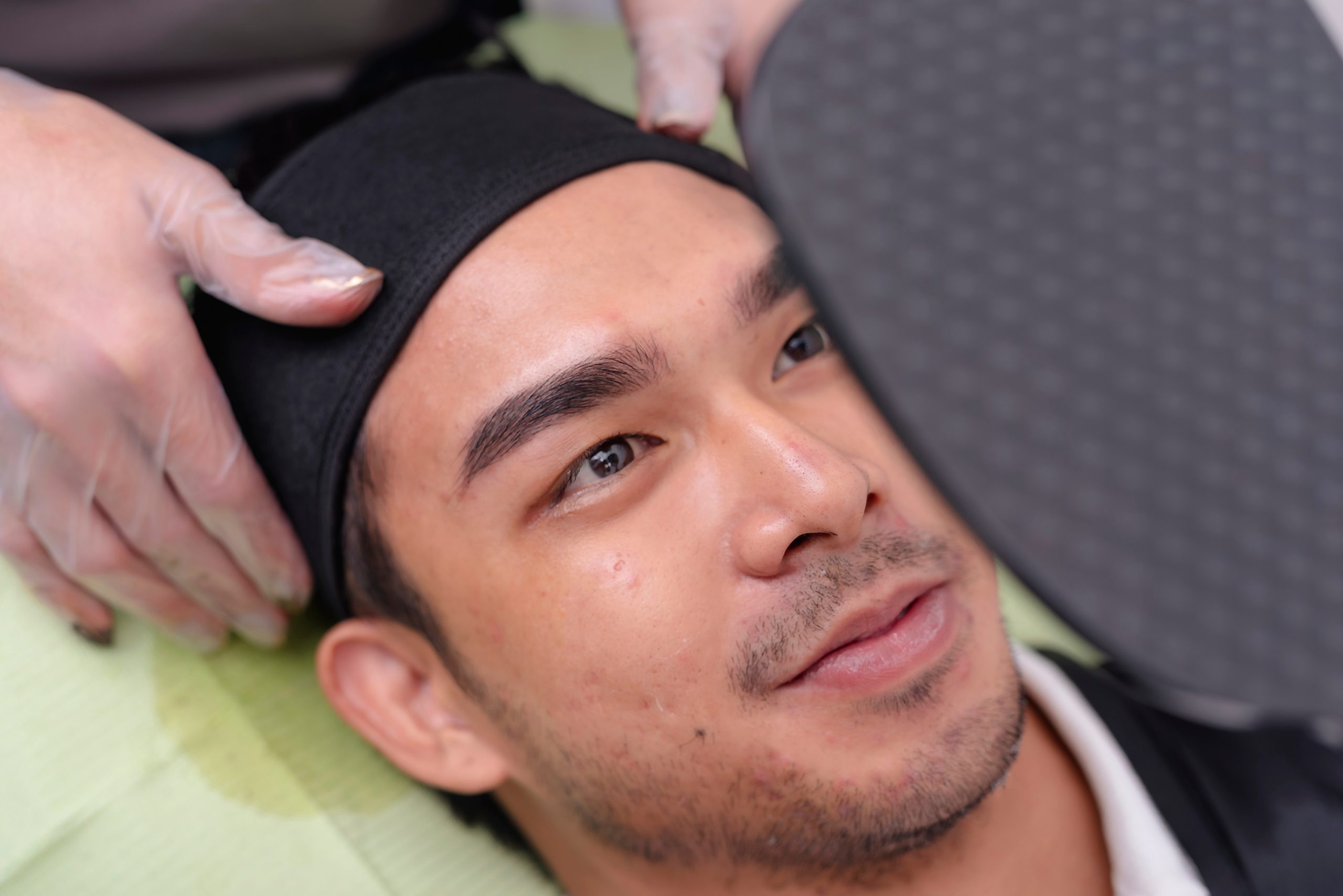 Man receiving laser hair removal treatment on eyebrows with protective eyewear during procedure