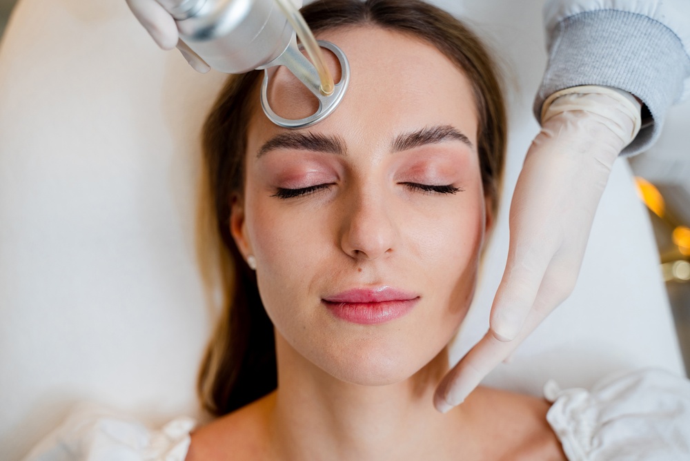 Cosmetologist performing CO2 laser resurfacing on patient's face to reduce wrinkles and scars