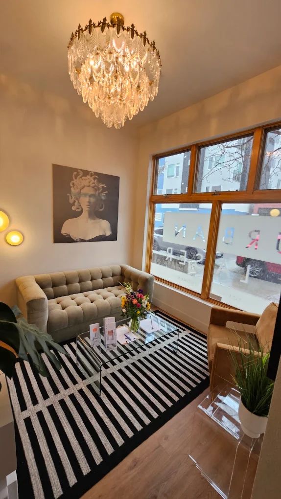 Urban Laser Denver waiting room with cream sofa, crystal chandelier, and street-facing windows