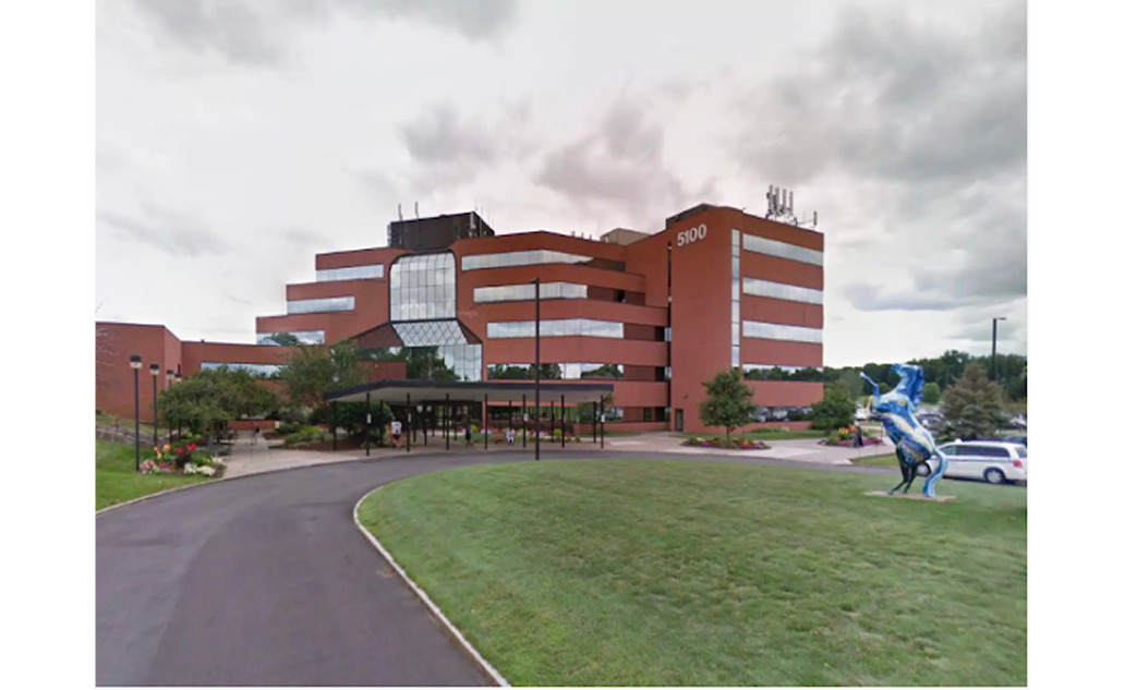 Modern red-brick dental building with glass windows and blue sculpture in front lawn