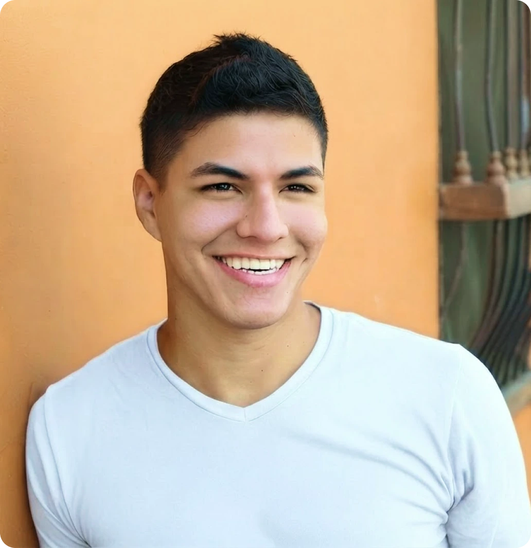 Smiling young man in a white t-shirt standing against an orange wall