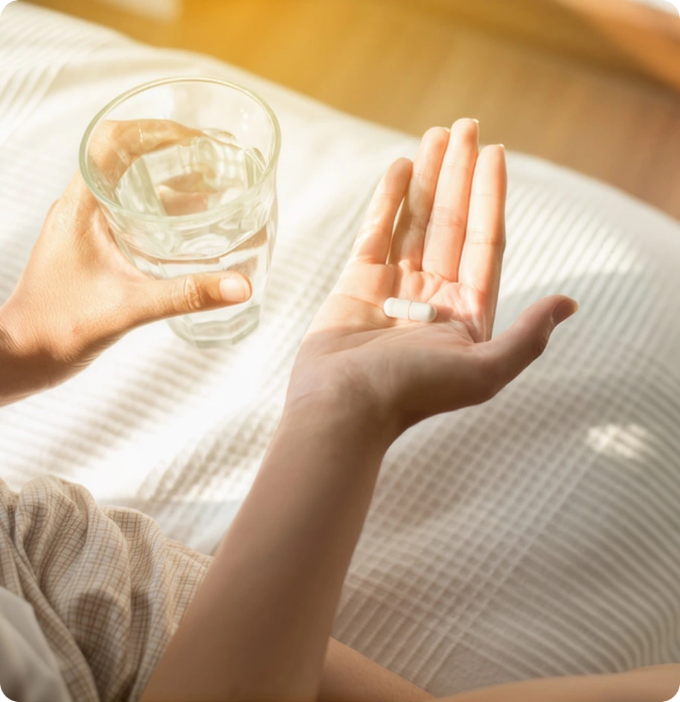 Person holding a medication capsule and a glass of water