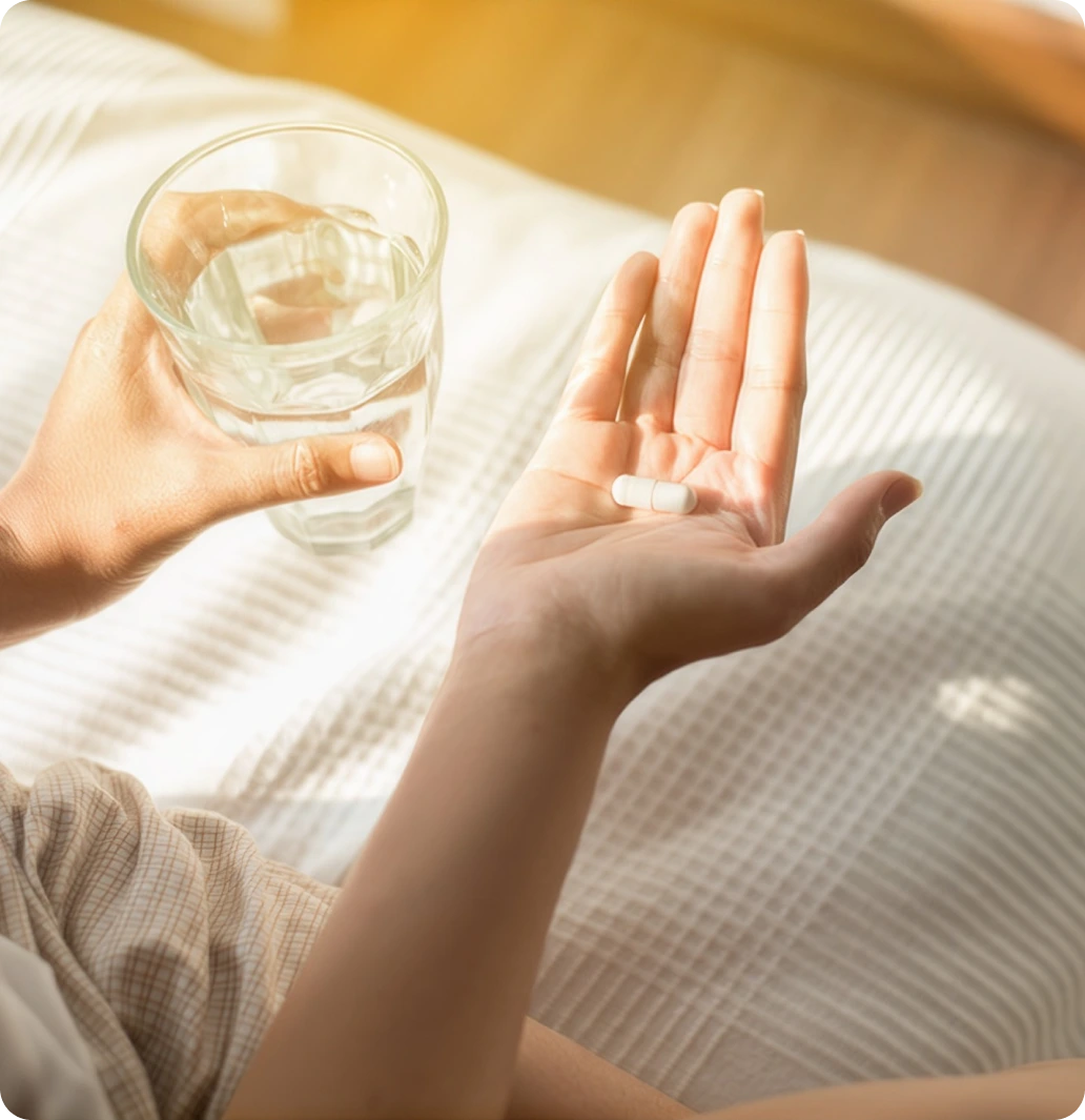 Person holding a medication capsule and a glass of water