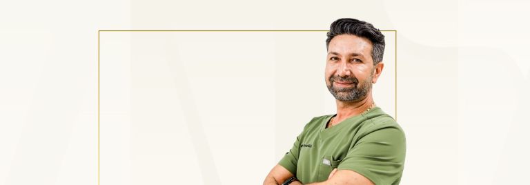 Man in green medical scrubs smiling at camera with arms crossed
