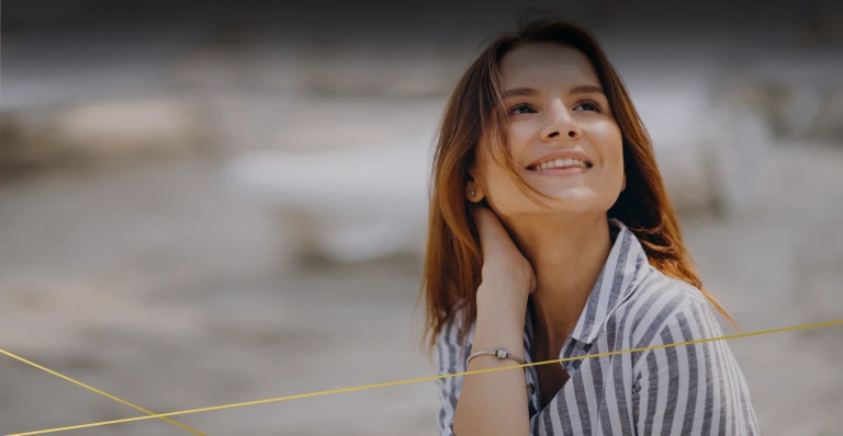 Smiling woman with long brown hair touching her neck and jawline