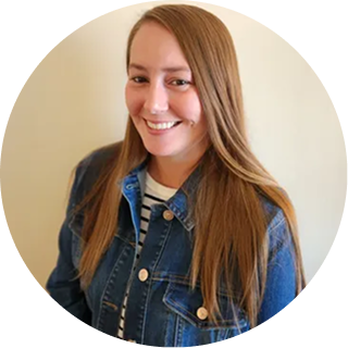 Woman with long reddish-brown hair wearing a denim jacket over striped shirt