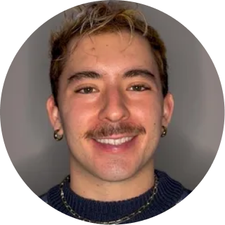 Man with light brown hair and mustache wearing dark sweater, smiling at camera