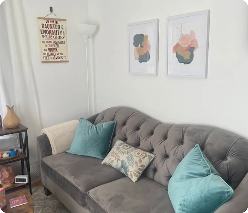 Therapy office with gray couch, turquoise pillows, motivational wall sign, and abstract artwork