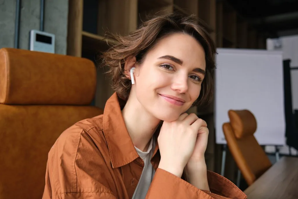 Woman in brown shirt smiling while sitting in modern therapy clinic interior