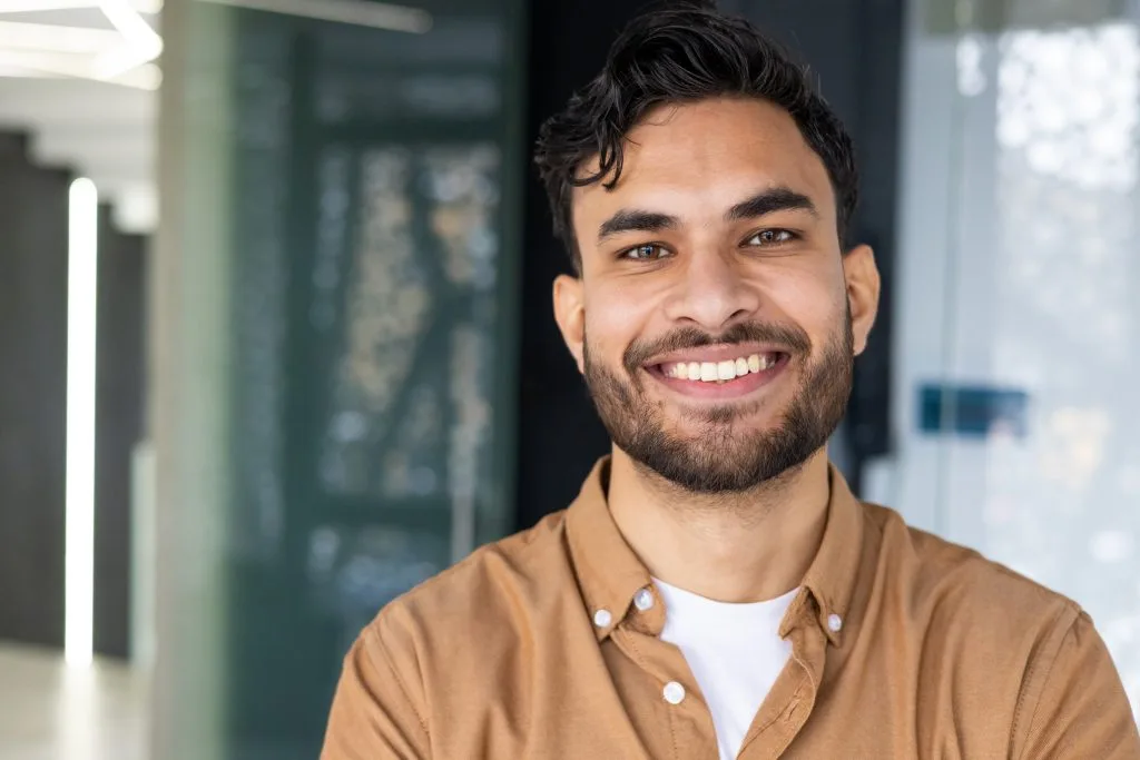 Man smiling at camera in modern clinic corridor with glass partitions