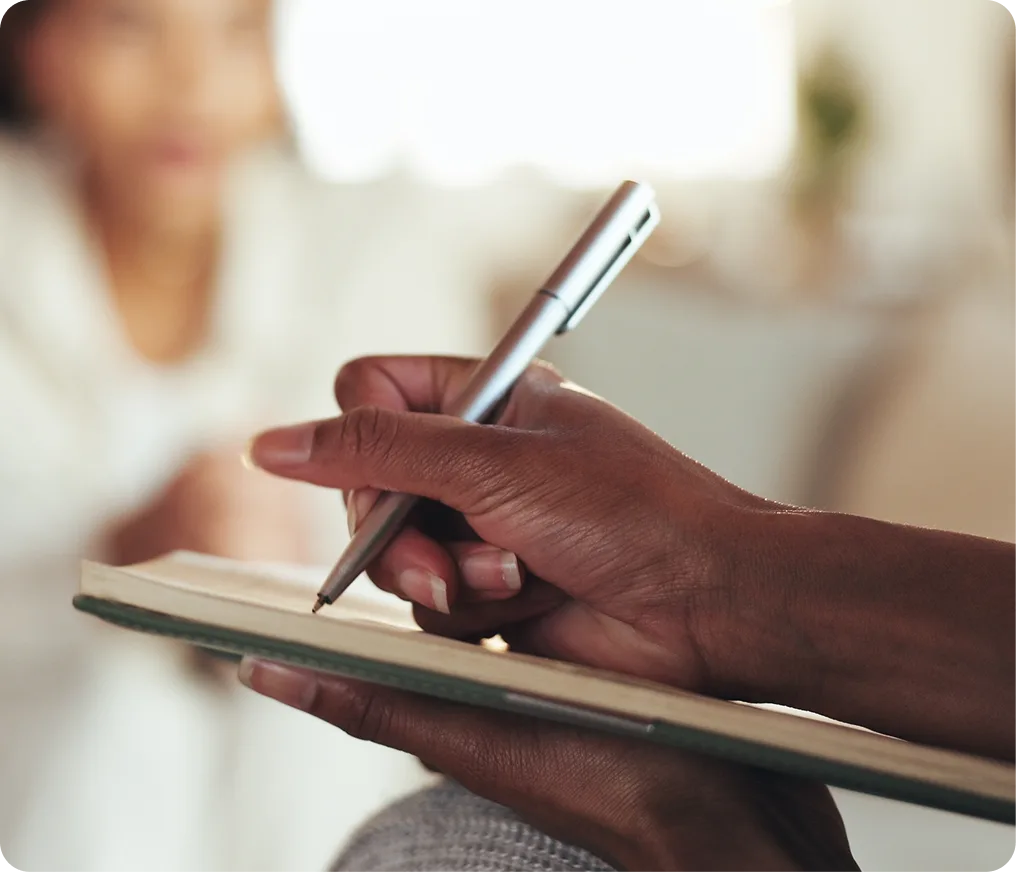 Person holding a pen and clipboard, writing during a consultation
