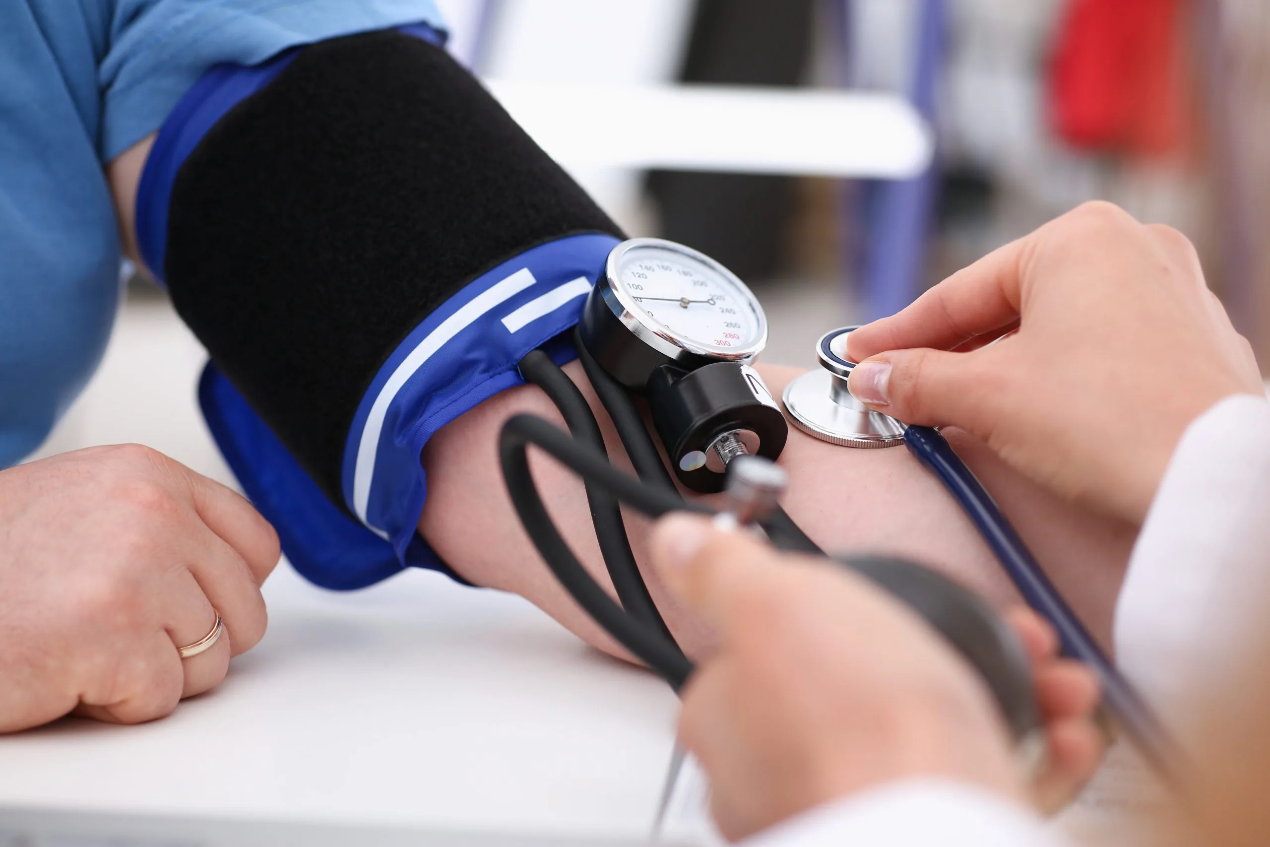 Healthcare provider using a blood pressure cuff and stethoscope to check a patient's blood pressure during a DOT physical examination