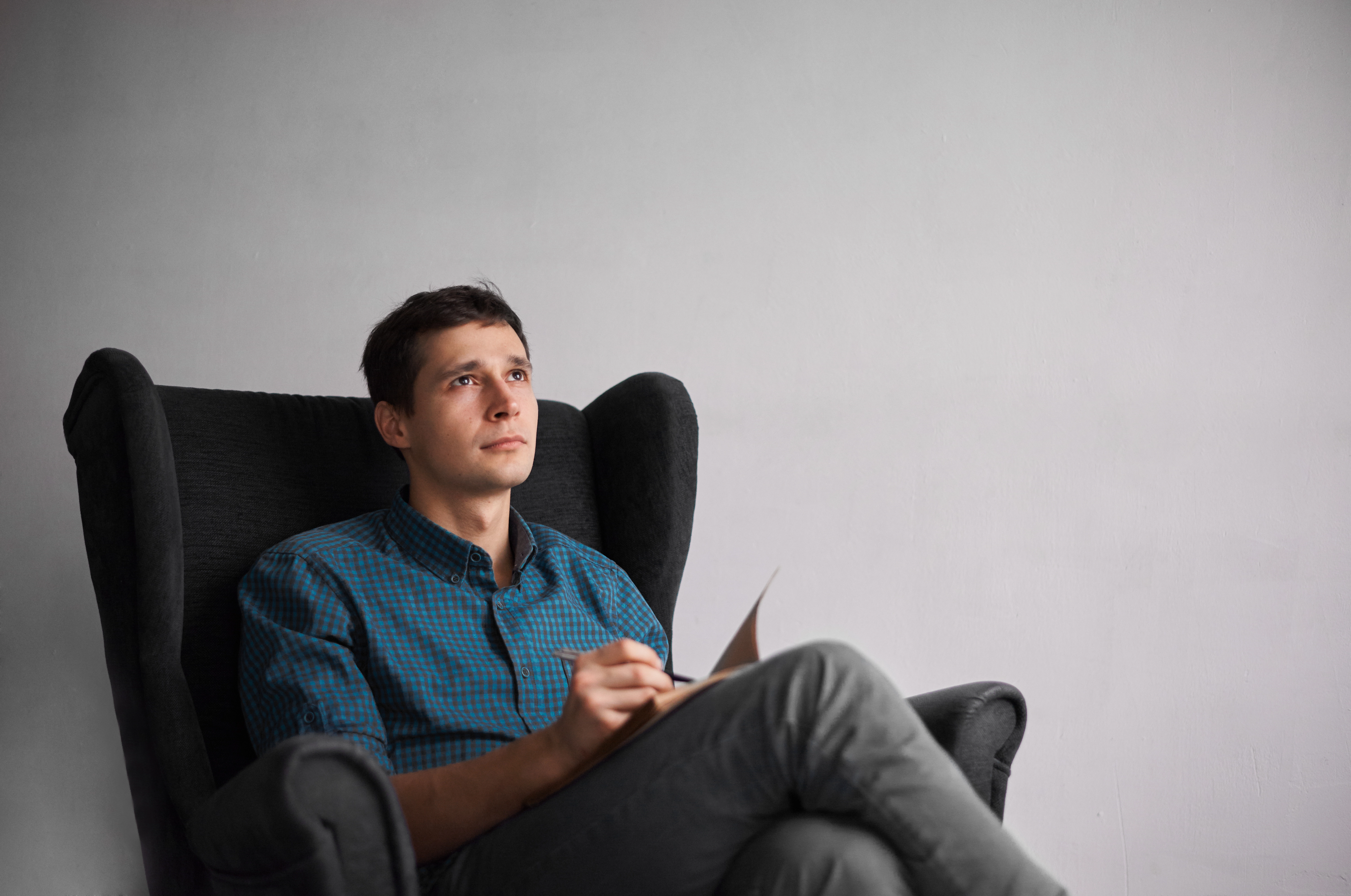 Man in a plaid shirt writing in a notebook
