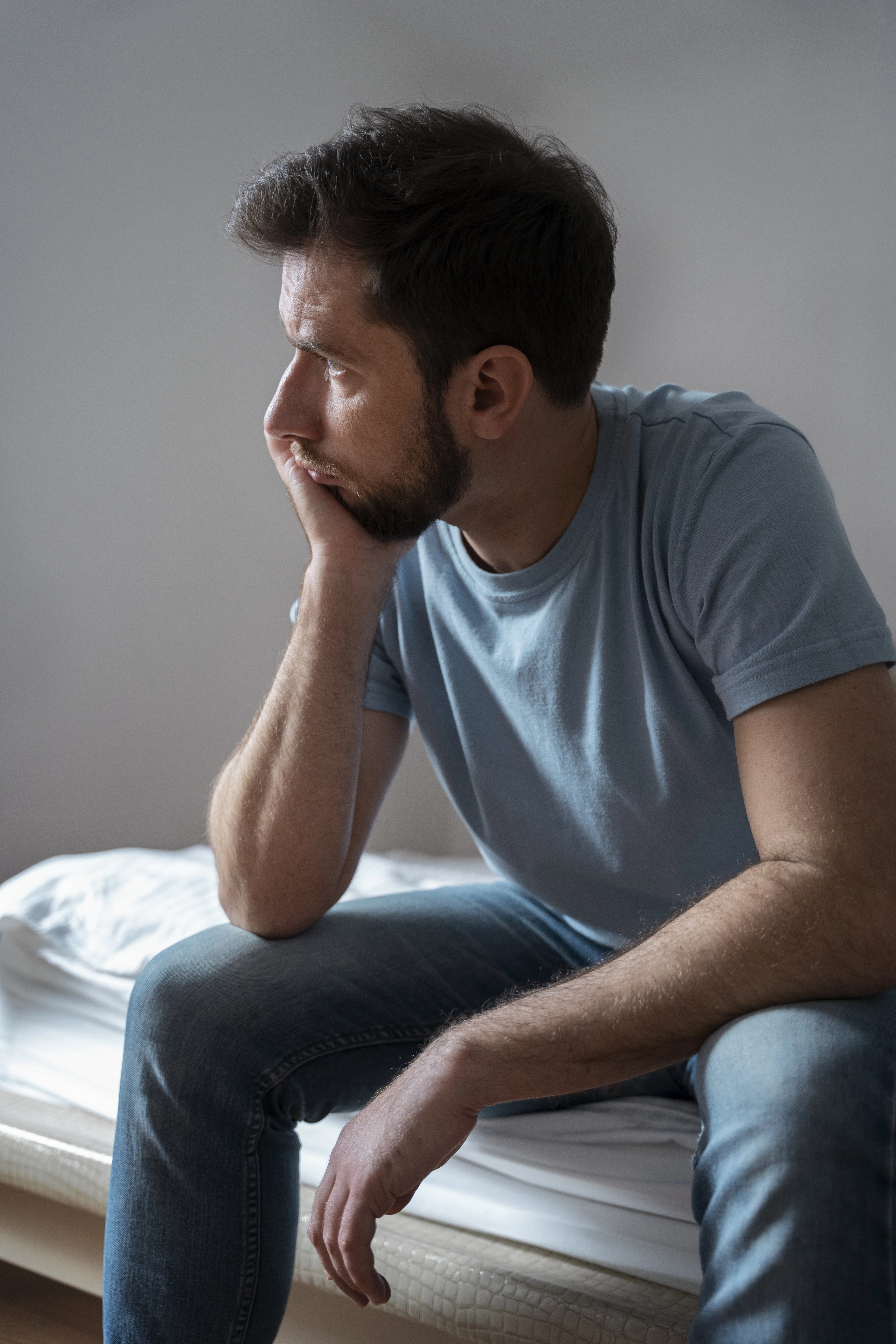 Man sitting on a bed looking thoughtful