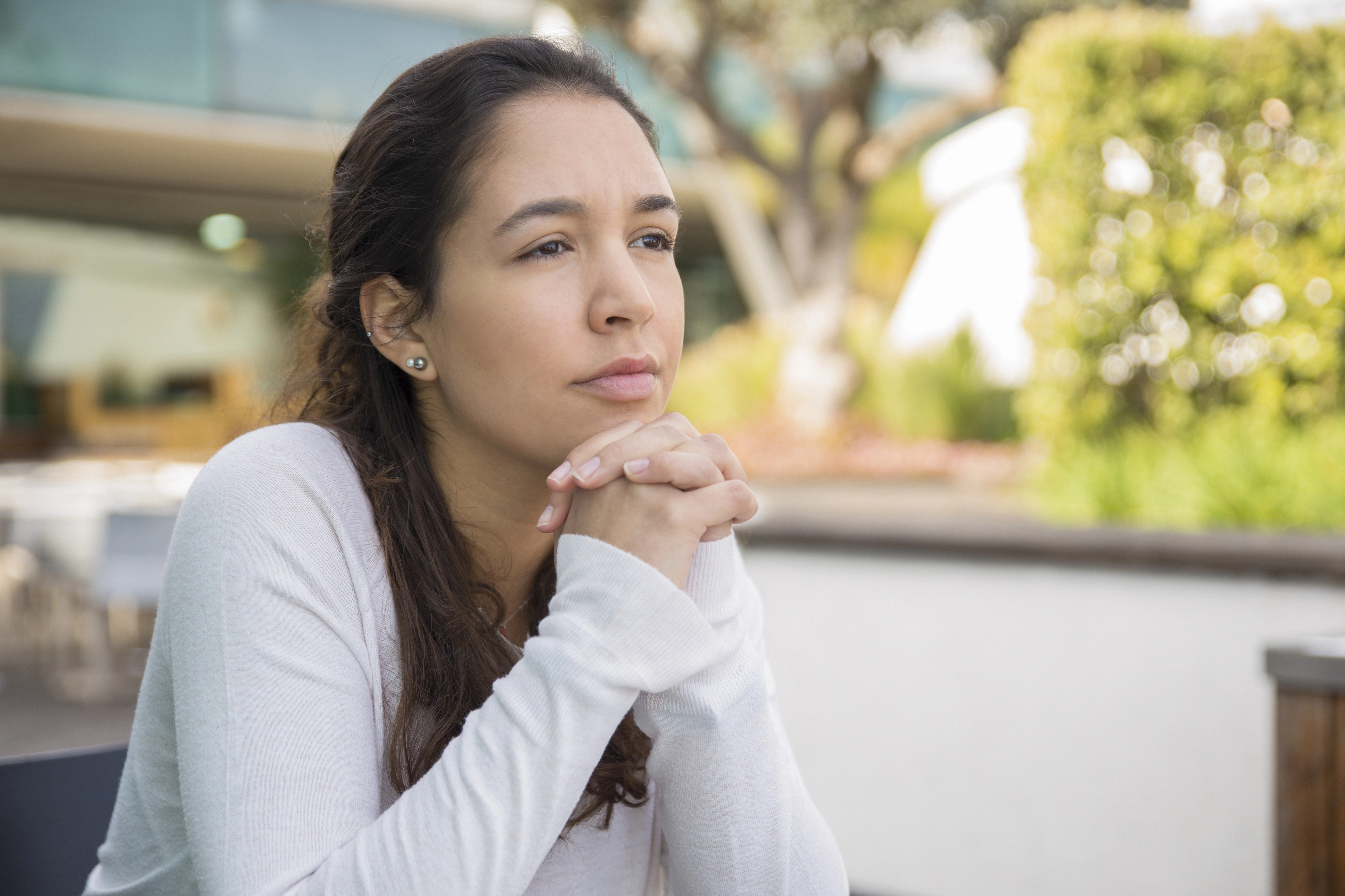 Pensive young woman sitting at a sidewalk cafe