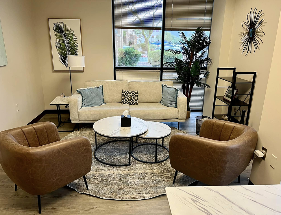 Modern dental office reception area with cream sofa, brown leather chairs, and round marble table