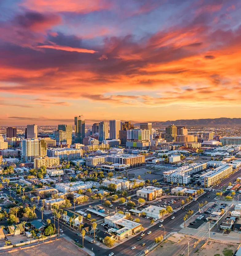 Phoenix cityscape at golden hour with downtown towers, residential areas, and mountains in background
