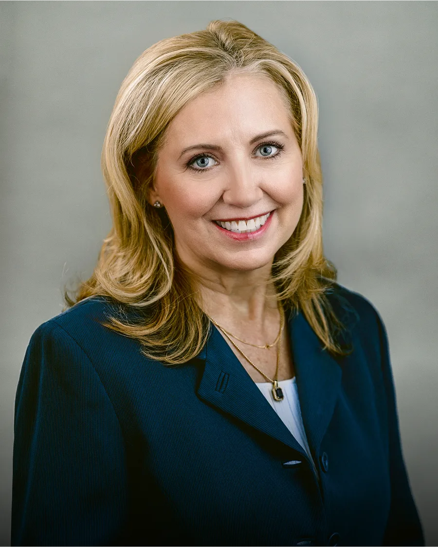 Professional headshot of woman with blonde hair wearing dark blue blazer