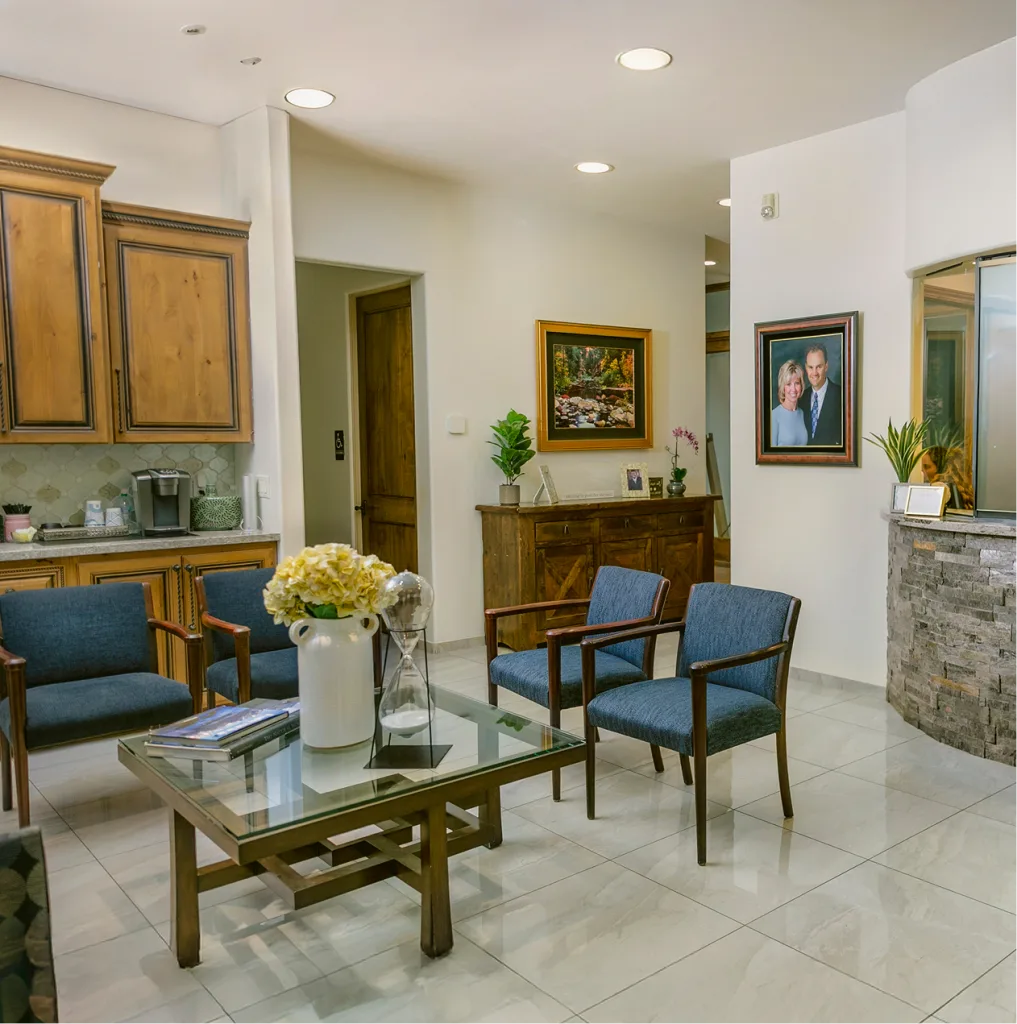 Modern dental practice waiting room with blue chairs, wood furniture, and stone fireplace