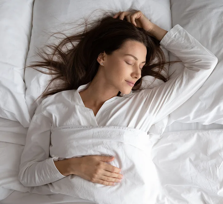 Woman sleeping peacefully on white bedding and pillow