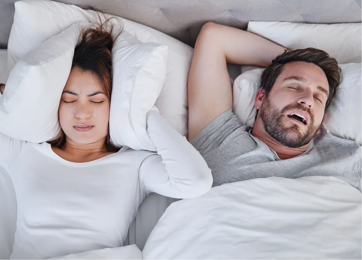 Man and woman sleeping peacefully in bed with white pillows and bedding