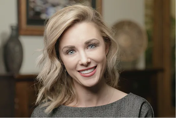 Woman with blonde wavy hair smiling at camera in dental office setting