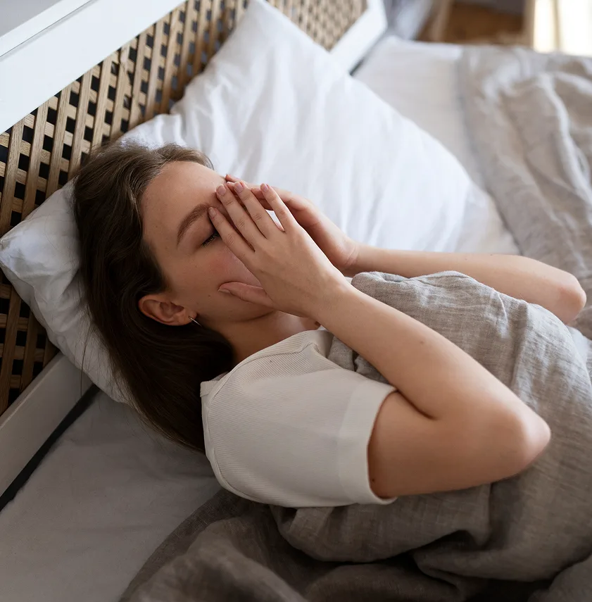 Woman lying in bed with hand covering her mouth while yawning
