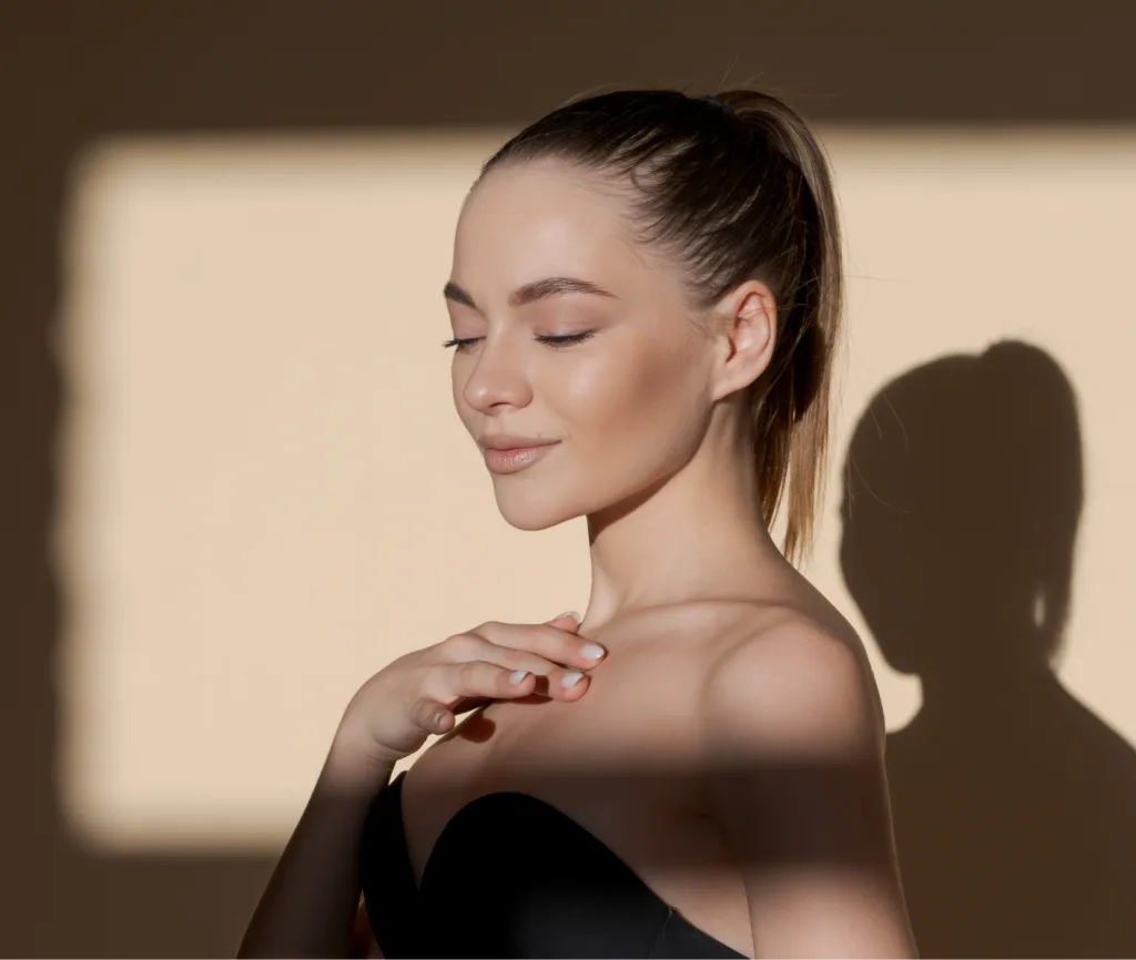 Woman in profile with pulled-back hair, eyes closed, hand near shoulder