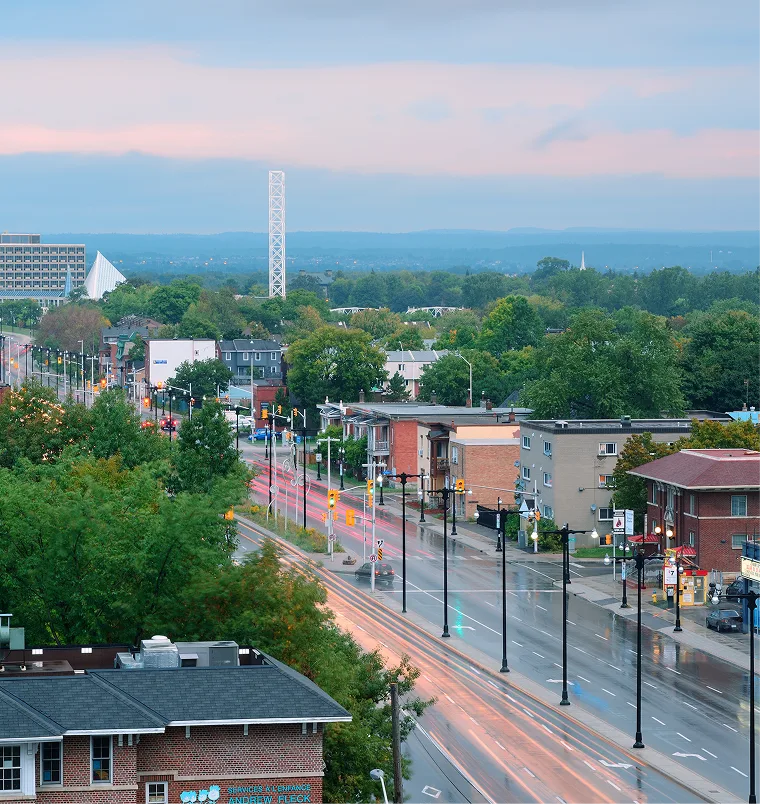 Aerial view of downtown street with brick buildings, storefronts, and mountain skyline at dusk