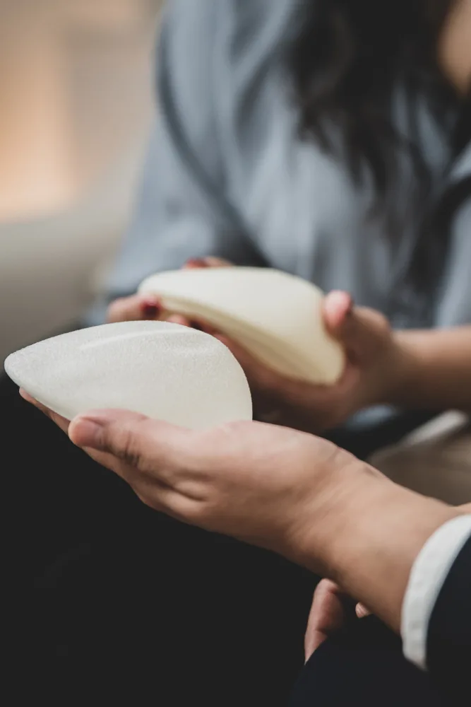 Hands holding two teardrop-shaped breast implant samples