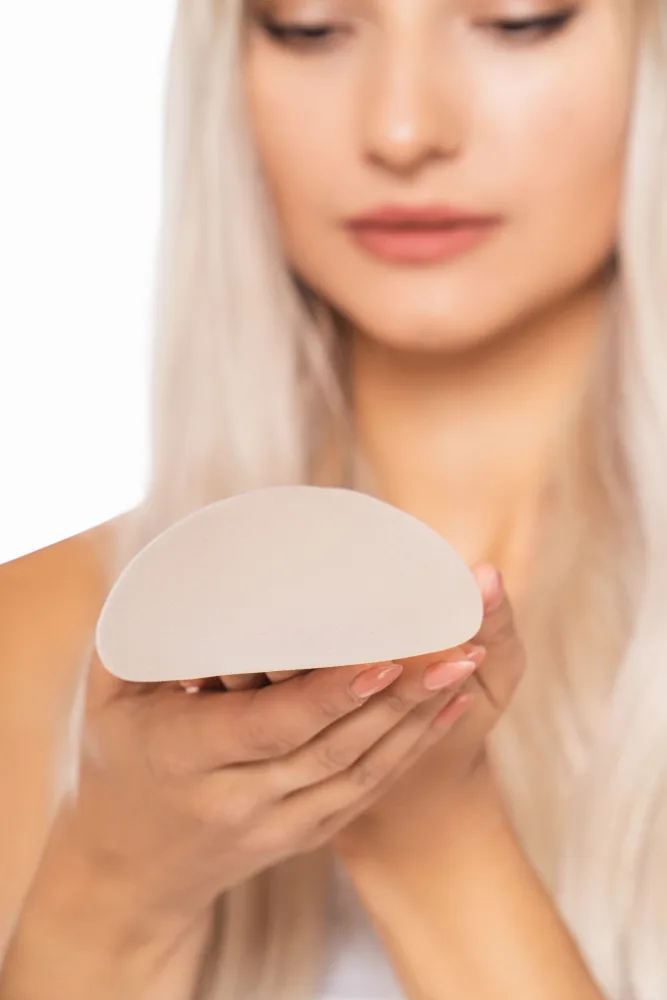 Woman holding teardrop-shaped silicone breast implant in both hands