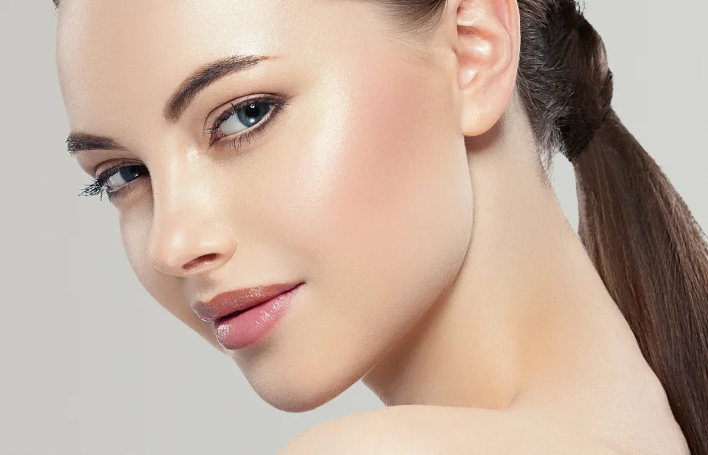 Woman's face in three-quarter profile view with pulled-back dark hair