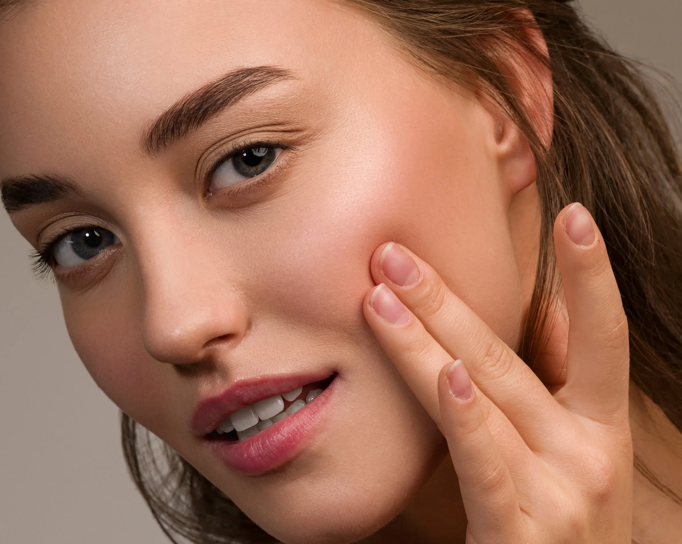 Woman touching her cheek, displaying clear, smooth facial skin