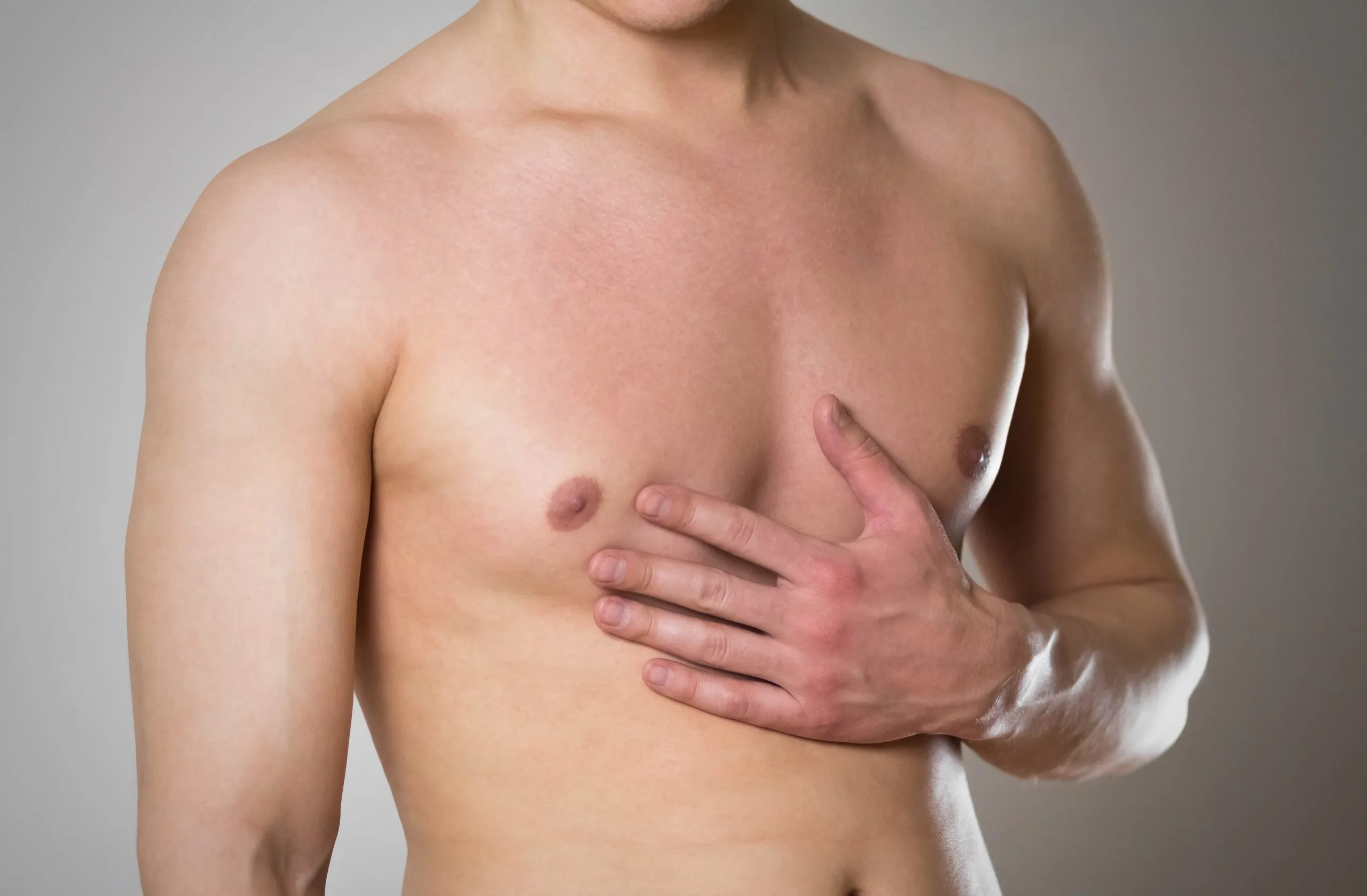 Shirtless man with hand on chest against gray background