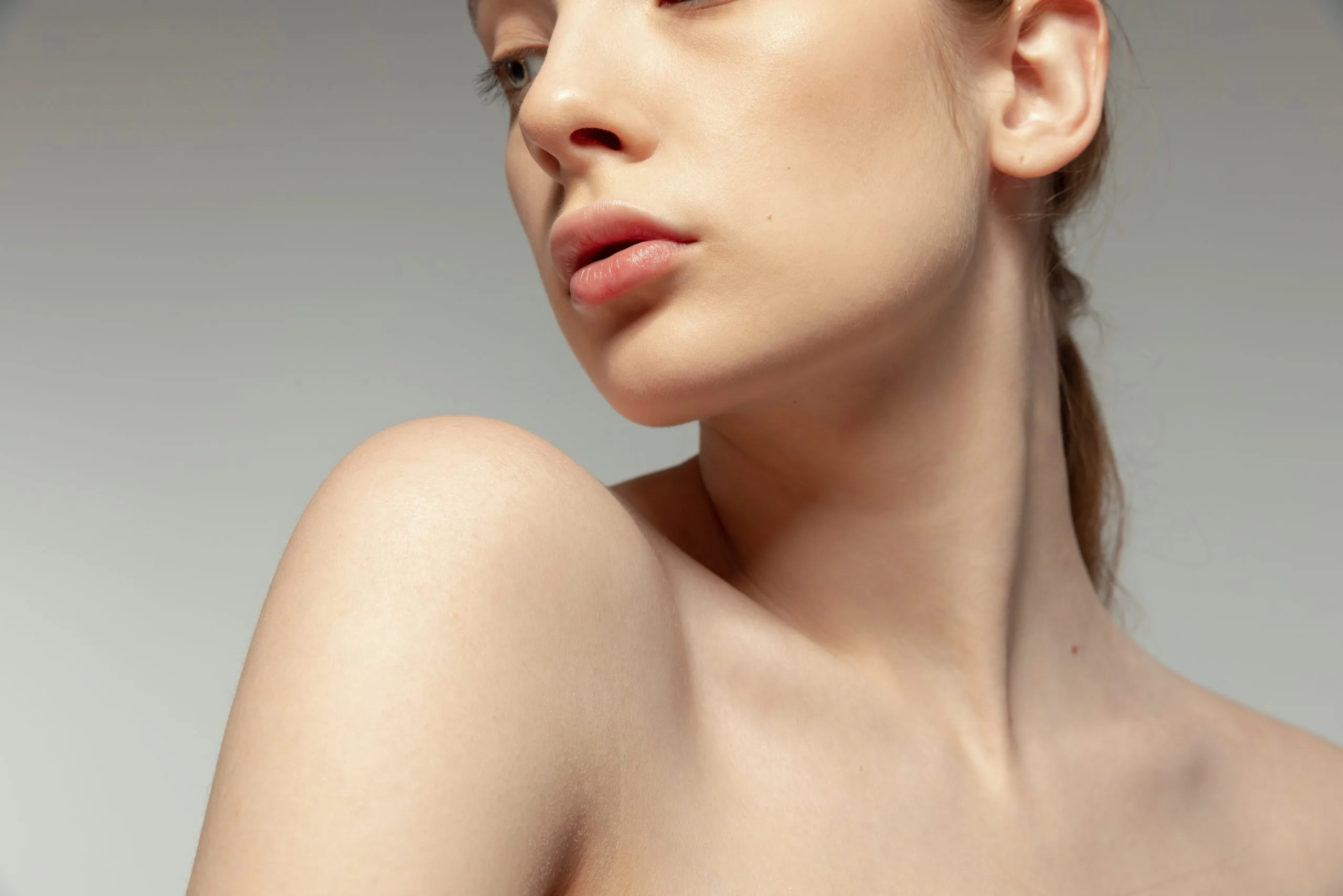 Woman in profile showing face and shoulder against neutral background