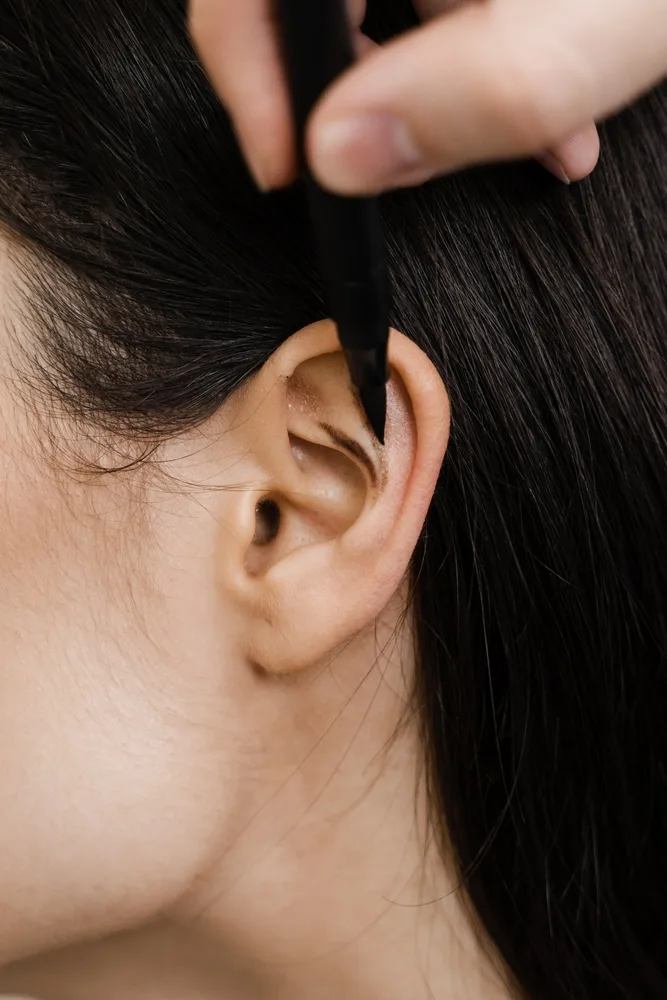 Hands examining patient's ear during consultation